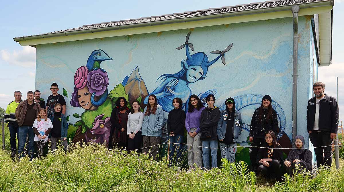 Schüler und Vertreter der ovag Netz GmbH vor einer gestalteten Fassade