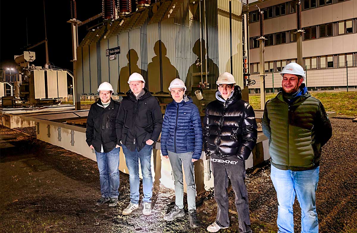 Gruppenfotor der Feuerwehr Rockenberg vor einem Transformator im Umspannwerk bei Dunkelheit.