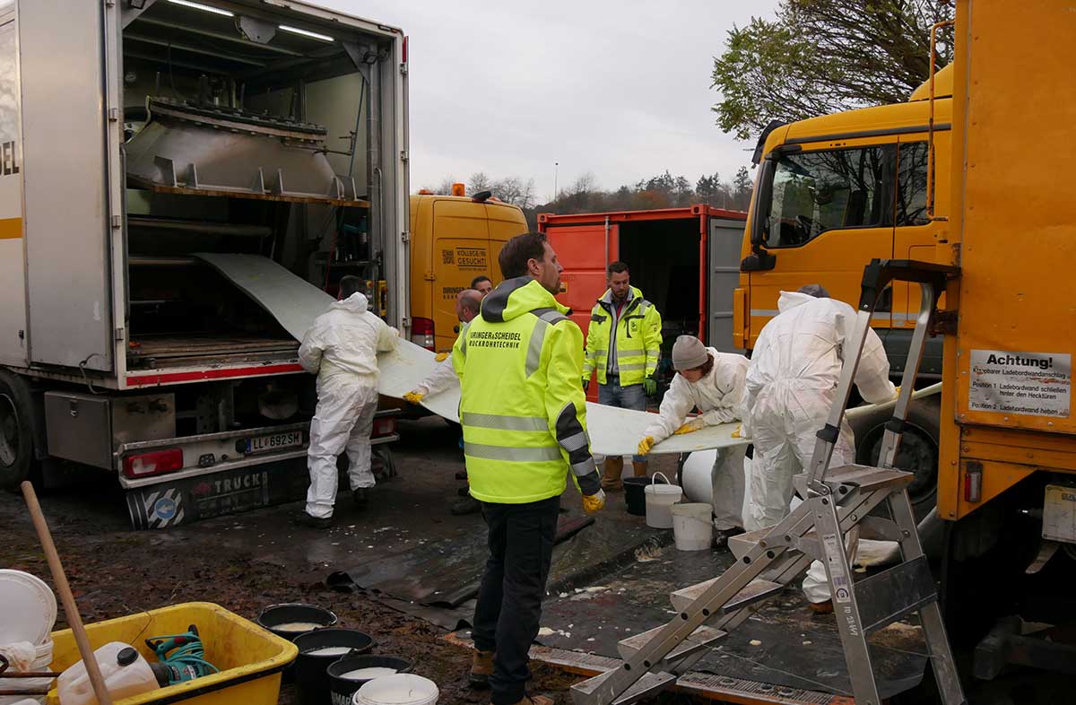 Der Schlauch wird durch das Wasserbad im LKW gezogen, wird dann per Hand eingeseift und danach in die Drucktrommel des anderen LKW aufgetrommelt, von wo aus er später wieder ausgeblasen wird.