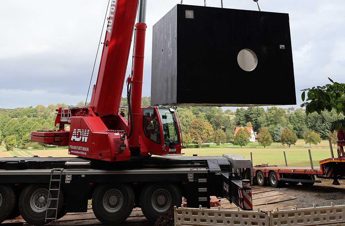 Der 20 Tonnen schwere Betonschacht wird in die Erde gelassen. Hier führt später das Wasserrohr hindurch.