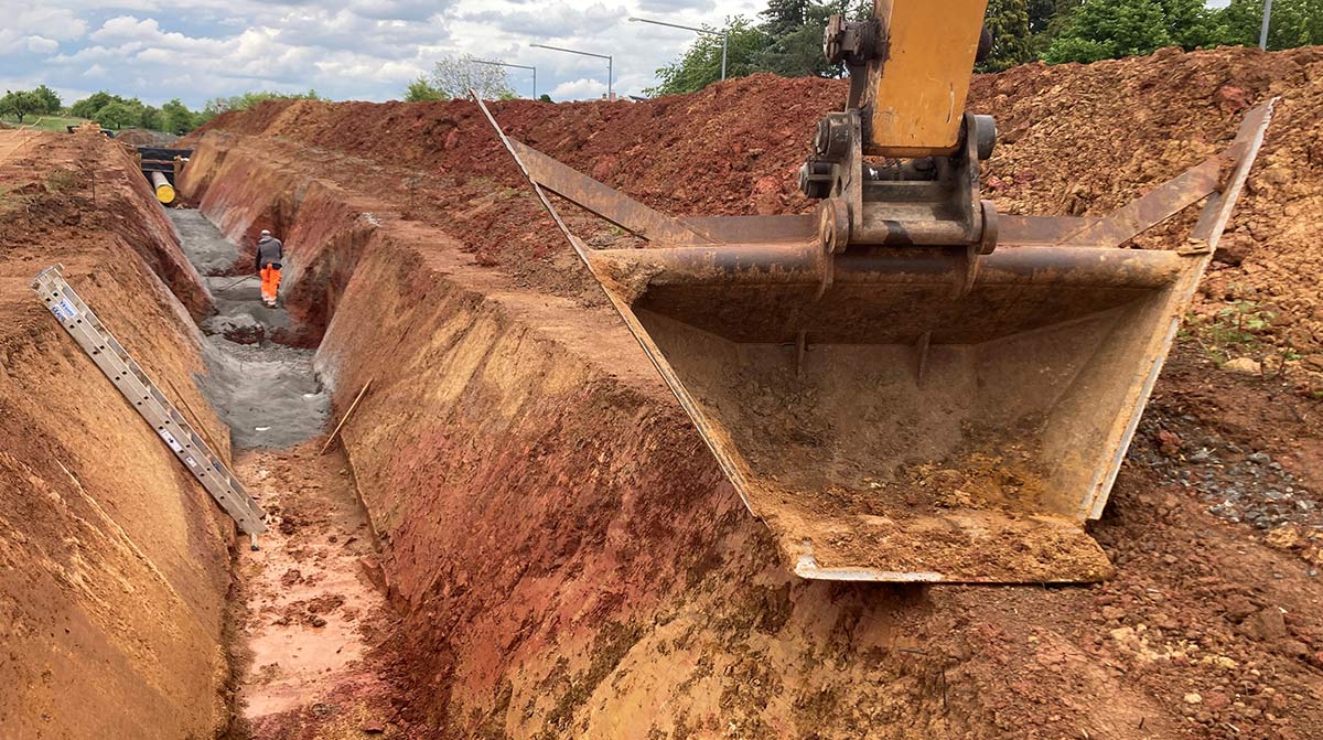 Baustelle mit langem Graben und Baggerschaufel