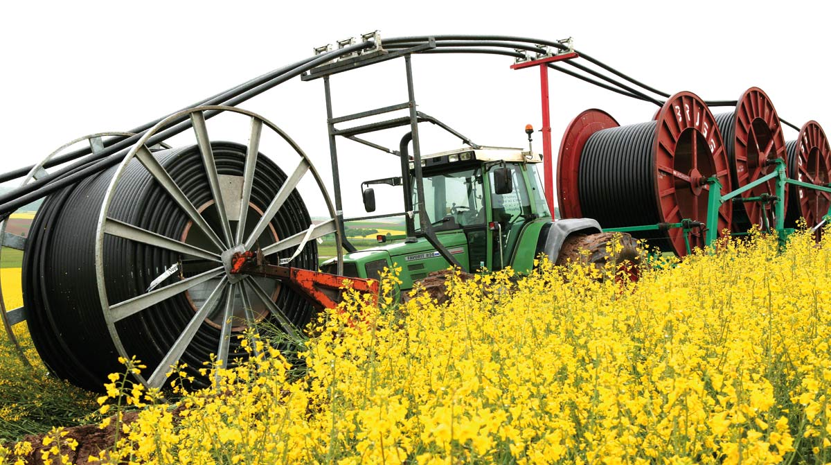 Traktor verlegt Erdkabel für Strom durch ein Rapsfeld