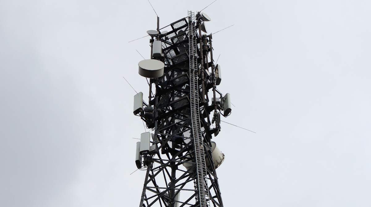 Ein großer Funkmast mit zahlreichen Antennen ragt in den grauen Himmel.